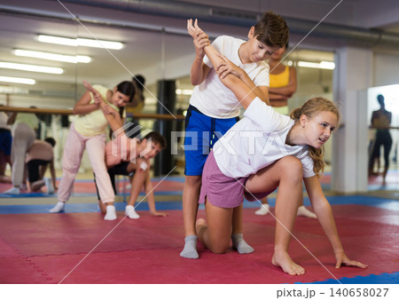 Girls and boys try to make painful grip on the attacker arm during training in self-defense lesson 140658027