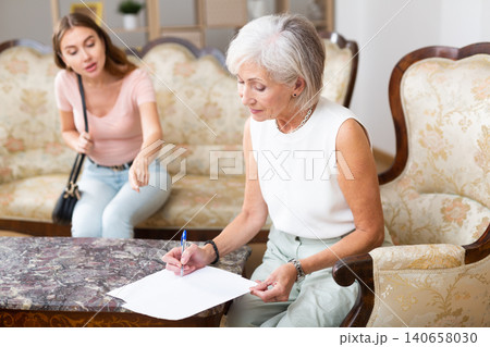 Woman realtor helping elderly woman to sign an apartment lease agreement 140658030