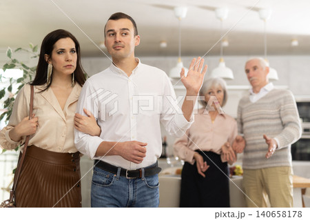 Exiting couple with man making cease argument gesture to parents Exiting couple with man making cease argument gesture to parents 140658178