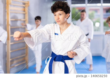 Group lesson in karate or taekwondo for kids in gym. Practicing kicks 140658250