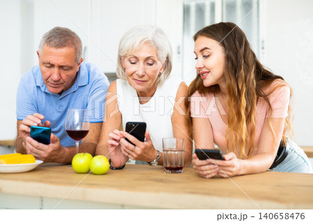Portrait of family using phones during dinner indoors 140658476