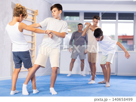 Sporty boys practices self-defence moves in pairs in sporty gym 140658499