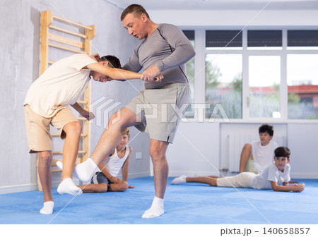 Skilled trainer demonstrating self-defense technique on juvenile practitioner Skilled trainer demonstrating self-defense technique on juvenile practitioner 140658857