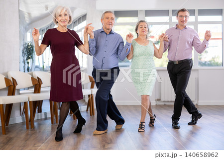 Smiling mature men and women dancing catalan typical Sardanas in dance salon 140658962