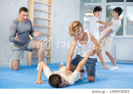 Diligent preteen student twisting his opponent's arm on the floor 140659085