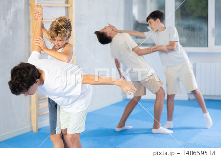 Concentrated preteen boys practicing effective self defence techniques with coach in training room 140659518
