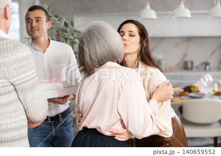 Happy young man and woman welcoming their senior parents at home 140659552