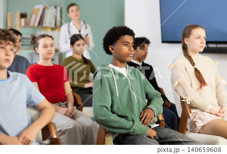 During meeting at class, teen pupil listen to lecture, doctor lecturer in background. During meeting at class, teen pupil listen to lecture, doctor lecturer in background. 140659608