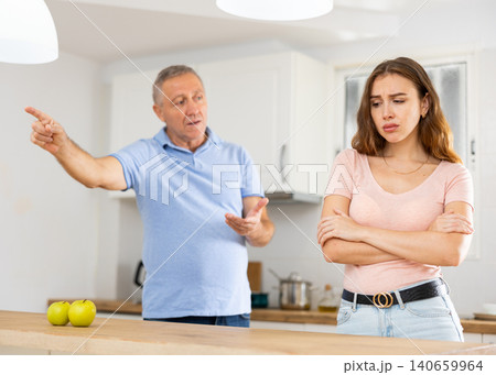 Elderly indignant father scolding adult daughter in kitchen Elderly indignant father scolding adult daughter in kitchen 140659964