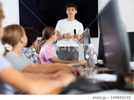 Guy teacher teaches group of students in computer class 140660138