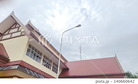 Modern Thai-style architecture building with tiled roof under a cloudy sky background photography 140660642