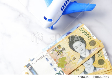 韓国の通貨、ウォンKRWの紙幣と飛行機で、韓国旅行に出発するイメージ 140660665