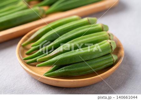 Fresh green okra on wooden plate, concept for organic vegetables and healthy eating Fresh green okra on wooden plate, concept for organic vegetables and healthy eating 140661044
