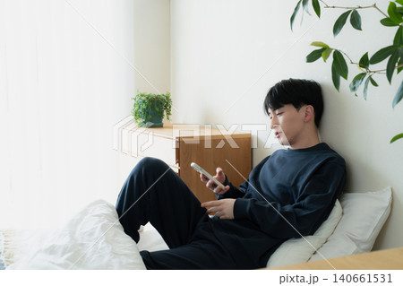 ベッドでスマホを見る若い男性 ベッドでスマホを見る若い男性 140661531