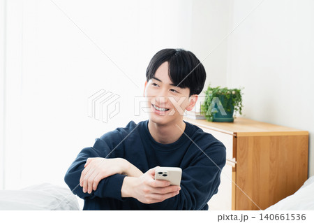 ベッドでスマホを見る若い男性 ベッドでスマホを見る若い男性 140661536