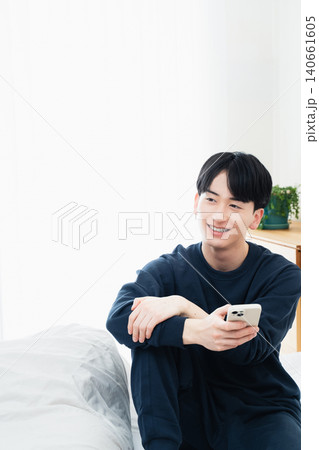 ベッドでスマホを見る若い男性 ベッドでスマホを見る若い男性 140661605