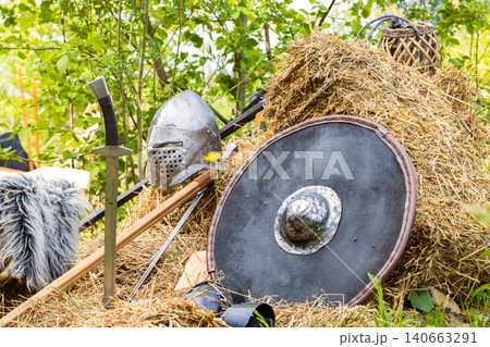 knight equipment weapon sword shield and helmet still life resting scene on stack of hay traditional festival outdoor view knight equipment weapon sword shield and helmet still life resting scene on stack of hay traditional festival outdoor view 140663291