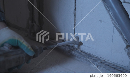 Worker Applying Sealant Along Floor Seam With Gloved Hand, Smoothing Bead Of Silicone Between Tile And Wall Using Caulking Tool, Dim Worksite Lighting And Focused Manual Motion Conveying 140663490