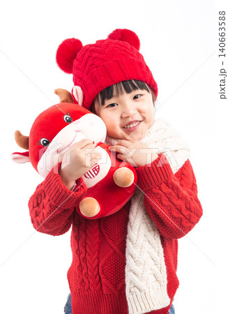 Smiling little girl hugging a red ox plush toy, celebrating the Year of the Ox, Chinese New Year theme.The Chinese character embroidered above: "Fu" (Good Fortune) Smiling little girl hugging a red ox plush toy, celebrating the Year of the Ox, Chinese New Year theme.The Chinese character embroidered above: "Fu" (Good Fortune) 140663588
