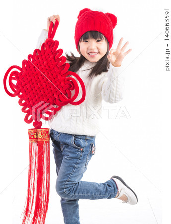 Happy Asian little girl holding a large Chinese knot ornament isolated on white background, celebrating Lunar New Year.There is a Chinese character on it: "Fu" (Good Fortune). Happy Asian little girl holding a large Chinese knot ornament isolated on white background, celebrating Lunar New Year.There is a Chinese character on it: "Fu" (Good Fortune). 140663591