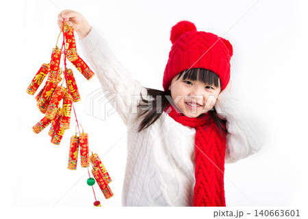 Cute Asian girl in red dress holding firecracker decorations and smiling, Chinese New Year celebration concept. Cute Asian girl in red dress holding firecracker decorations and smiling, Chinese New Year celebration concept. 140663601