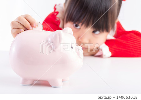 Little Asian girl putting a coin into a pink piggy bank, concept of saving money and financial education for kids. 140663618