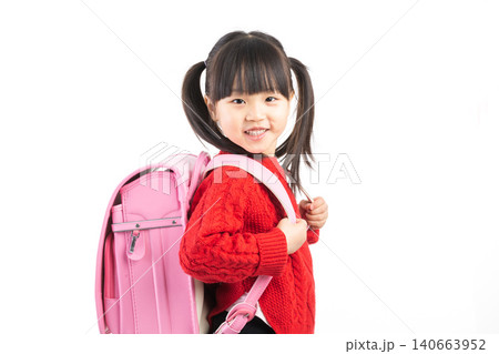Portrait of a smiling Asian girl wearing a red sweater and pink school bag isolated on white background. Portrait of a smiling Asian girl wearing a red sweater and pink school bag isolated on white background. 140663952