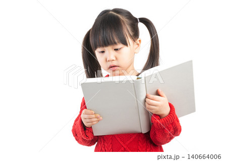 A focused little girl with pigtails looking down and reading an open book intently against a white background. A focused little girl with pigtails looking down and reading an open book intently against a white background. 140664006