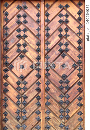 Old wooden gate leaf parts. Ancient wood door with metal rivets. Medieval wooden door with aged iron reinforcements Old wooden gate leaf parts. Ancient wood door with metal rivets. Medieval wooden door with aged iron reinforcements 140664083