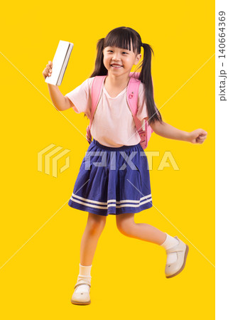 Cheerful young Asian girl in school uniform holding white notebook and wearing pink backpack while stepping forward Cheerful young Asian girl in school uniform holding white notebook and wearing pink backpack while stepping forward 140664369