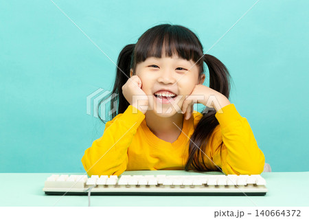 Smart young girl leaning on a computer keyboard and looking at the camera with a subtle smile. 140664372