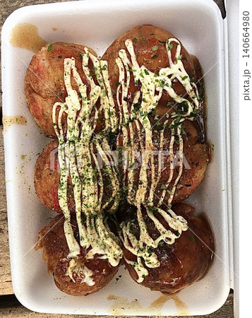 Takoyaki, a popular Japanese street food, are crispy round dough balls filled with octopus, tempura bits, and pickled ginger, topped with takoyaki sauce, bonito flakes, and aonori. Takoyaki, a popular Japanese street food, are crispy round dough balls filled with octopus, tempura bits, and pickled ginger, topped with takoyaki sauce, bonito flakes, and aonori. 140664980