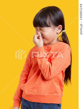 Cute Asian schoolgirl pinching nose, child reacting to bad smell on yellow background, disgust and hygiene concept Cute Asian schoolgirl pinching nose, child reacting to bad smell on yellow background, disgust and hygiene concept 140665248