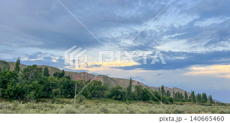 Scenic panoramic view of rolling green hills under a blue cloudy sky Scenic panoramic view of rolling green hills under a blue cloudy sky 140665460