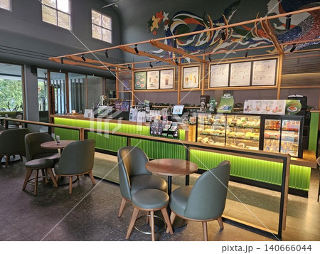 Modern coffee shop interior featuring a vibrant illuminated green service counter, stylish wooden bar. Modern coffee shop interior featuring a vibrant illuminated green service counter, stylish wooden bar. 140666044