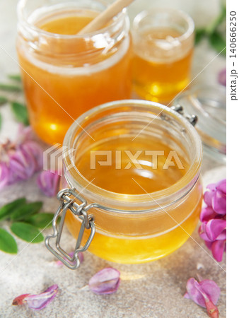 Acacia honey in glass jar surrounded by flowers 140666250