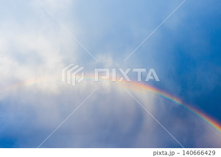 A vibrant rainbow arcs across a moody blue sky A vibrant rainbow arcs across a moody blue sky 140666429