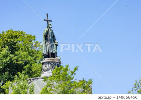 Statue of a historical figure holding a cross in a park during daytime with blue sky above. 06.21.2025. Kyiv. Ukraine Statue of a historical figure holding a cross in a park during daytime with blue sky above. 06.21.2025. Kyiv. Ukraine 140666450
