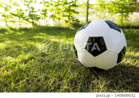 Classic black and white soccer ball on a grass, representing an iconic symbol of the Soccer World Cup and global football events. 140666632