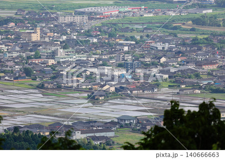 西南戦争の激戦地・高熊山から望遠で望む、田植え時期の伊佐市盆地の水田と街並み 140666663