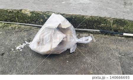 Plastic bag filled with garbage abandoned on dirty soil ground. Plastic bag filled with garbage abandoned on dirty soil ground. 140666693