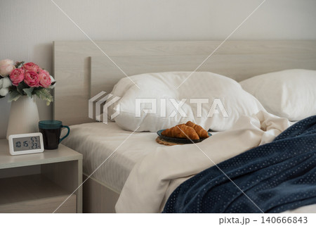 Cozy bedroom breakfast with croissants and coffee beside an unmade bed Cozy bedroom breakfast with croissants and coffee beside an unmade bed 140666843