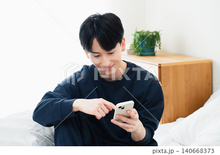 ベッドでスマホを見る若い男性 140668373