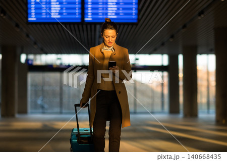 Woman Checking Train Schedule at Station with Suitcase Woman Checking Train Schedule at Station with Suitcase 140668435