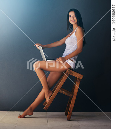 Laptop, portrait and woman on chair in studio with gray wall background for social media. Computer, relax and underwear with happy young person leaning or rocking on stool for blogging or streaming Laptop, portrait and woman on chair in studio with gray wall background for social media. Computer, relax and underwear with happy young person leaning or rocking on stool for blogging or streaming 140668657