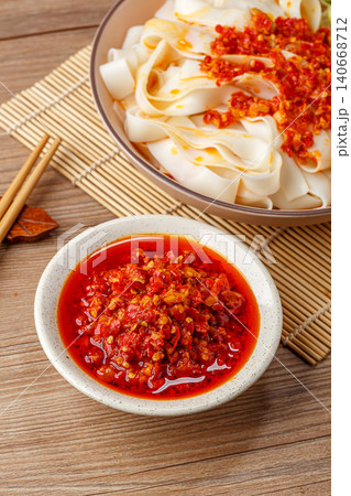 Traditional Chinese chopped red chili paste in a small bowl with a noodle dish background. Traditional Chinese chopped red chili paste in a small bowl with a noodle dish background. 140668712