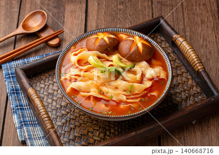 Chinese traditional knife-cut noodles in rich tomato soup with shiitake mushrooms on a wooden tray. Chinese traditional knife-cut noodles in rich tomato soup with shiitake mushrooms on a wooden tray. 140668716