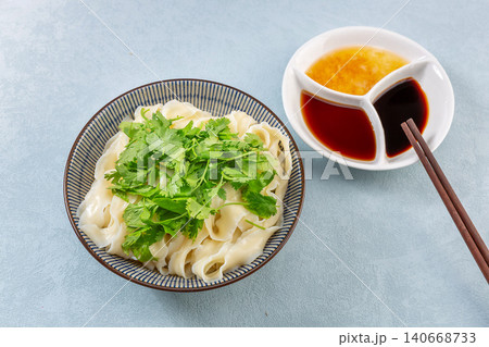 Refreshing dry mixed flat noodles topped with fresh minced garlic sauce and cucumber shreds Refreshing dry mixed flat noodles topped with fresh minced garlic sauce and cucumber shreds 140668733