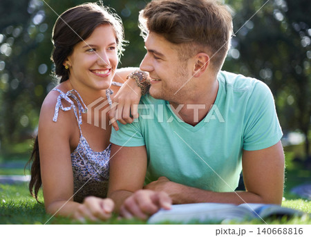 Students, couple and book for reading on grass with smile, hug and lying in sunshine at university. People, studying and scholarship for knowledge, education and information with embrace at college Students, couple and book for reading on grass with smile, hug and lying in sunshine at university. People, studying and scholarship for knowledge, education and information with embrace at college 140668816