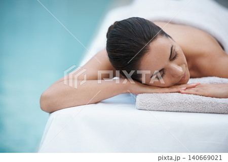 Luxury, spa and woman relax for massage on table at hotel pool, calm and care for body in holiday. Vacation, outdoor and female person on getaway for weekend and resort with treatment for skincare 140669021